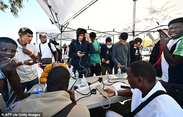 Texas migrants are seen charging their phones after being dropped off from a San Diego train station on October 10