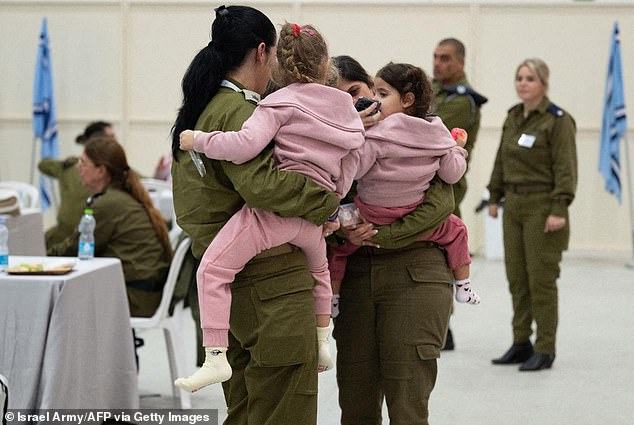 A pair of female IDF soldiers comfort Raz, four, and Aviv, two, after their release