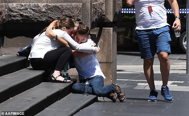 Pictured: People hugging each other on the corner of Bourke and Elizabeth Street after a car plowed through pedestrians on January 20, 2017