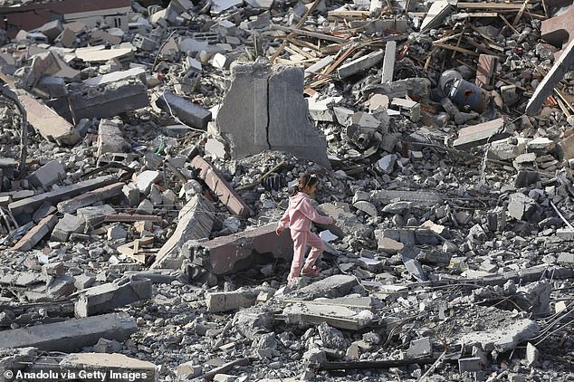 A Palestinian girl tries to walk among the wreckage of buildings after Israeli attacks during the third day of the humanitarian pause in Khan Yunis