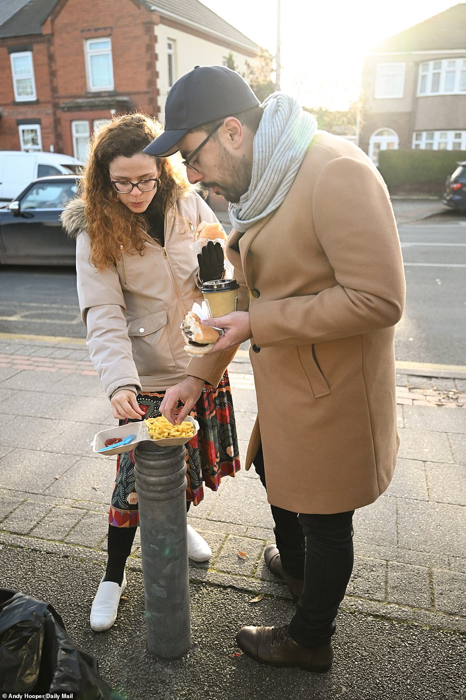 A few visiting fans eat chips from a bollard outside The Turf Pub's butty van, which sits near the ground