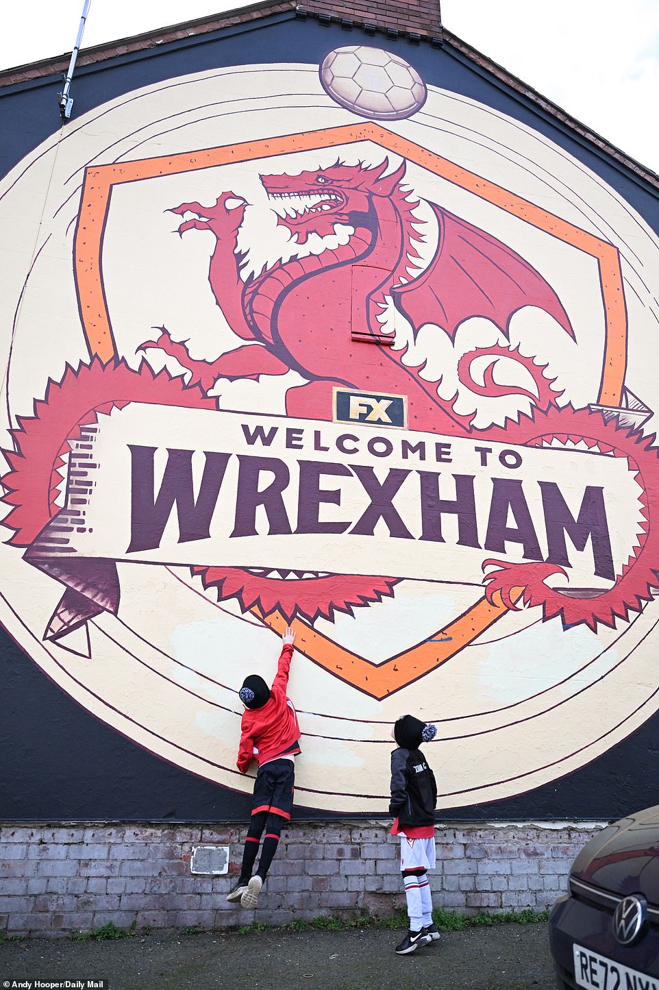 Young fans play in front of a local mural that shows the city's pride in their League Two football team