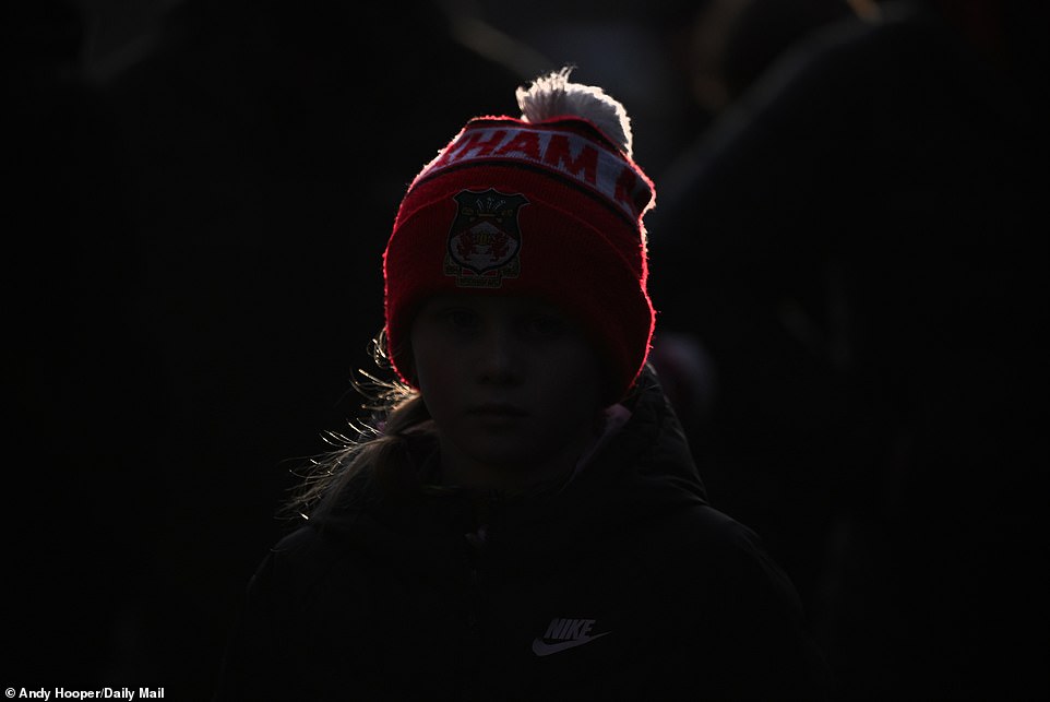 A winter silhouette of a young fan in November, wearing a bright red Wrexham hat in support of their team