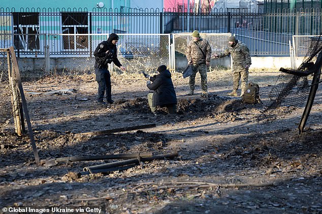 Police and military officers investigate a crater from a drone, which exploded in the courtyard of a residential building in the Solomianskyi district