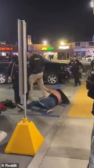 The woman tried to sit up after being pushed down but was stopped by a police officer