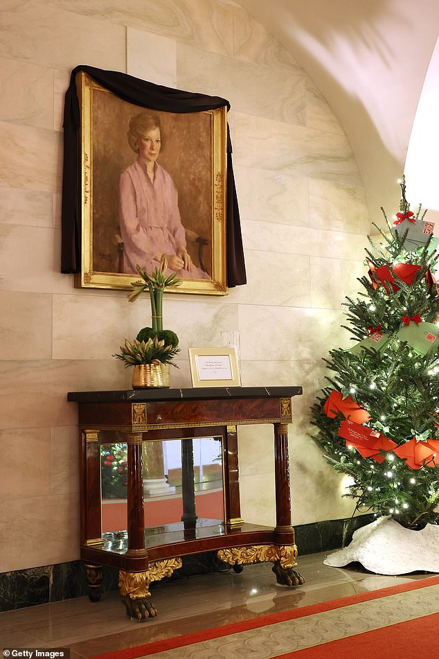 A portrait of former first lady Rosalynn Carter is wrapped in black garland among the White House Christmas decorations