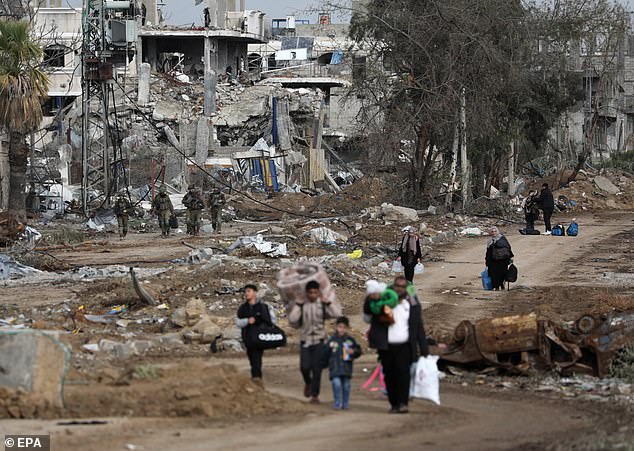 Palestinians walk after crossing from the northern Gaza Strip to the southern Gaza Strip as Israeli soldiers move along the Salah Al Din Road in the central Gaza Strip, November 28, 2023