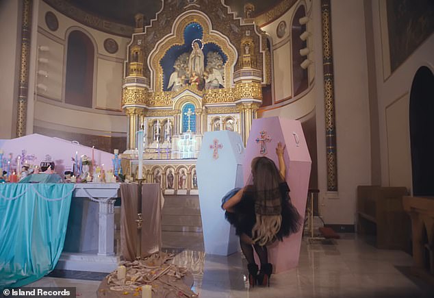 The singer then sensually weaves around the pastel coffins of ex-boyfriends piled at the altar, one of which is decorated with the motif 'RIP B*****'