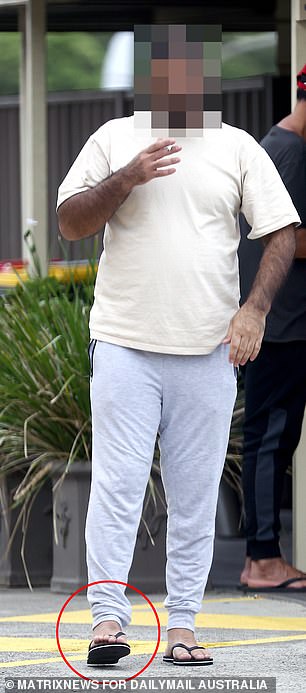 In the photo: a man covers his anklet with his sweatpants