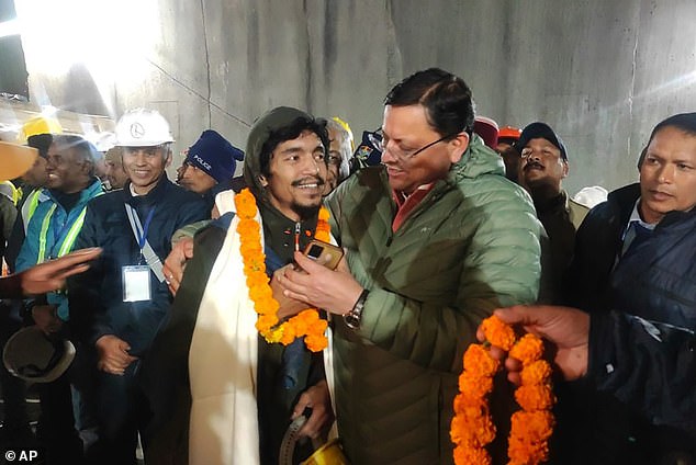 Pushkar Singh Dhami, right, chief minister of Uttarakhand state, greets a worker rescued from the tunnel in Silkyara, India, Tuesday, November 28, 2023