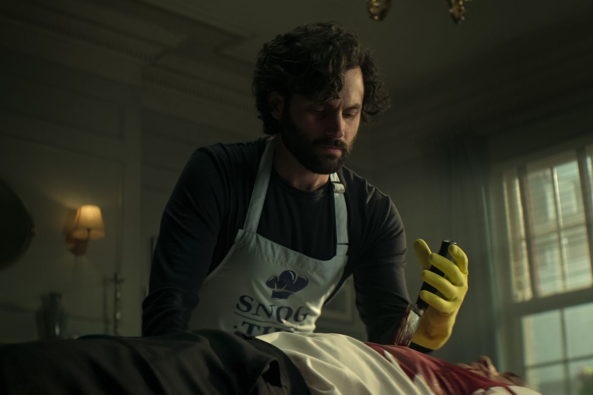 Penn Badgley as Joe Goldberg who pulls a knife from a dead man's chest in season four of You.