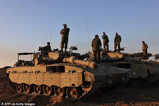 Israeli soldiers stand on tanks deployed on the southern border with the Gaza Strip on November 29, 2023, as a ceasefire between Israel and Hamas entered a sixth day