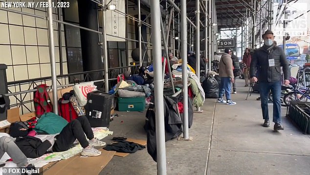 The migrants line up outside a hotel in downtown Manhattan with all their belongings