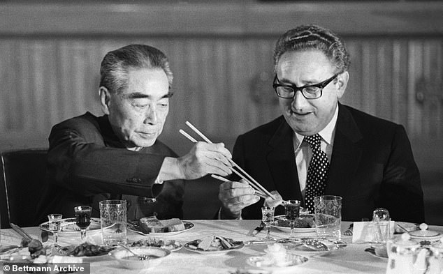 Kissinger accepts food from Chinese Premier Zhou Enlai during a state banquet at the Great Hall of the People in Beijing