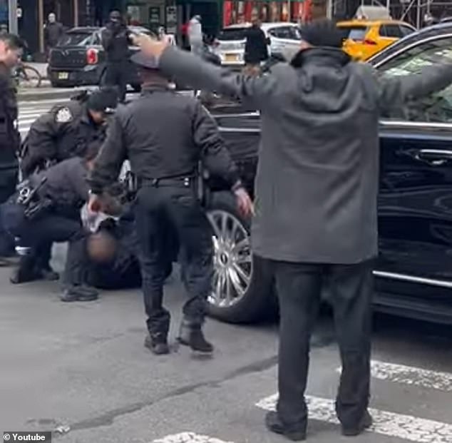 The irate driver is seen getting out of the vehicle and helping to pull the man off the hood after seeing him crack his windshield