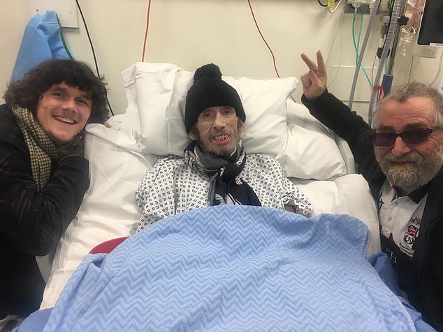 MacGowan (centre) lying in his hospital bed in a photo shared by his wife Victoria