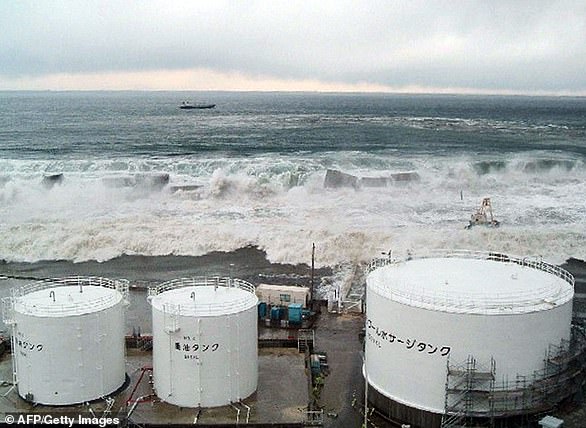 Tsunami waves crash over the sea wall towards TEPCO's Fukushima Daiichi nuclear power plant in Okuma