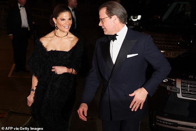 Crown Princess Victoria opted for a striking black dress with a scarf and a feather texture as she arrived with Prince Daniel
