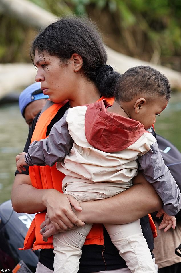 A migrant with a toddler boards a boat with other migrants heading north, in Bajo Chiquito in Panama's Darien Province, Thursday, Oct. 5, 2023, after walking across the Darien Gap from Colombia