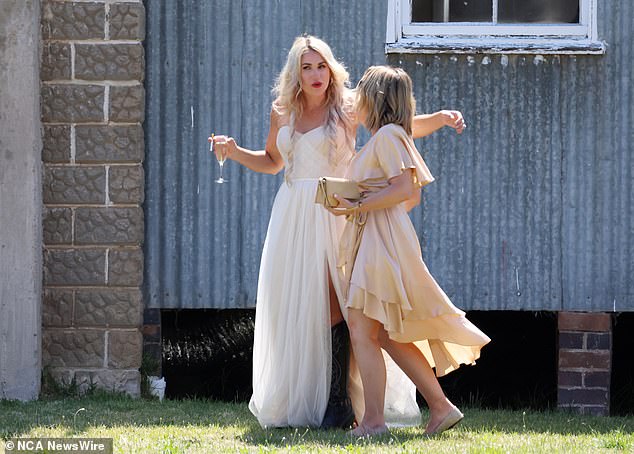 Mrs Campion wore a strapless cream dress with gold earrings and black heeled cowboy boots as she walked next to her new husband with a post-ceremony glass of champagne and a cigarette in hand, smiling broadly at her guests (pictured)