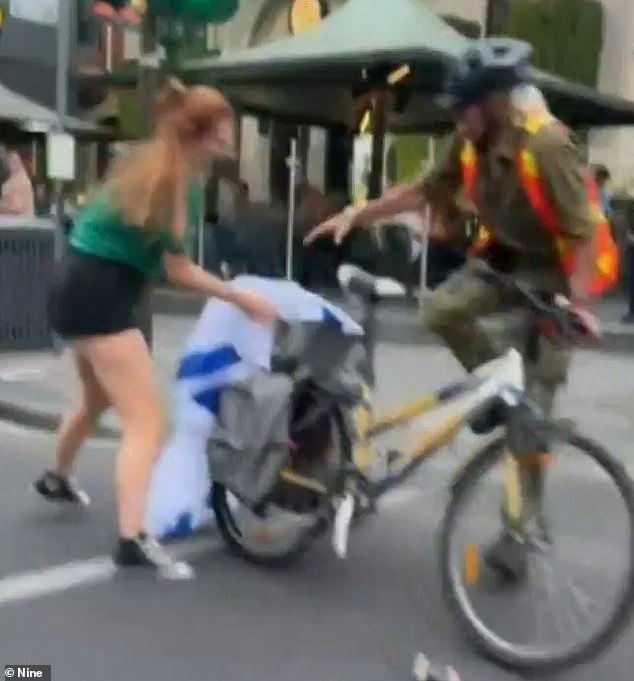 Video shows a woman chasing Ronen Martin-Cohen and trying to grab the Israeli flag from his bicycle