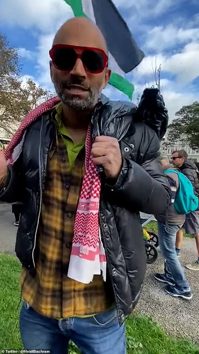 The man, who was carrying a large Palestinian flag at the time, was wearing a brown checked shirt, blue jeans and a black jacket.