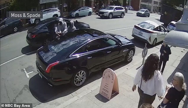 Armed robbers try to steal a car in Oakland.  Violent crime is rampant in California city, with business owners now comparing the area to a 'battlefield' akin to wartime Vietnam