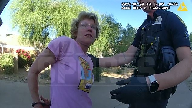 Pictured: Nicole Kugler Bidwell, wife of Bill Bidwill Jr., is seen handcuffed by a police officer outside her home in Paradise Valley, Arizona, during the June 9 domestic dispute in which she beat up her husband