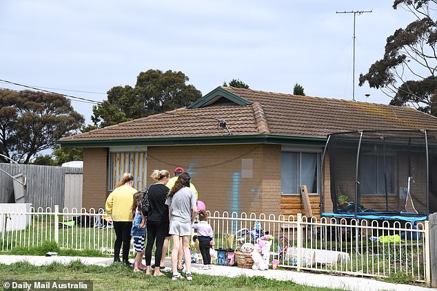 Community members gather at the makeshift memorial set up for the victims of the garage fire