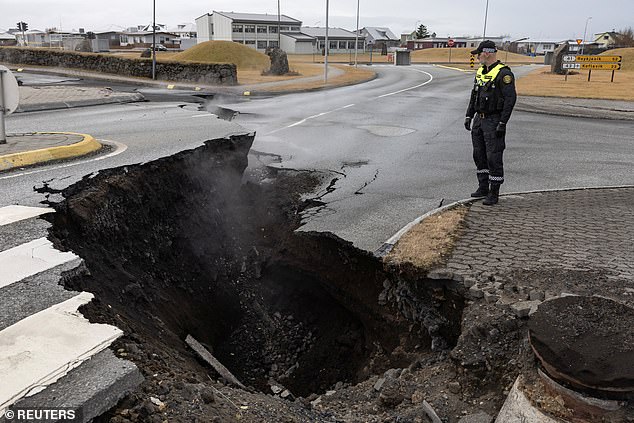 A police officer stands near the crack in a road in the fishing village of Grindavik, which was evacuated on Wednesday due to volcanic activity in Iceland