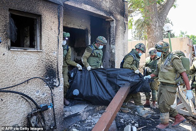 Israeli soldiers remove the body of a fellow countryman killed during an attack by Hamas terrorists in Kfar Aza, October 10