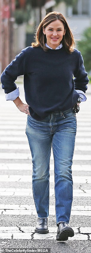 Take it easy: Garner cuts a casual figure as he wears a white button-up shirt under a navy blue crew-neck sweater