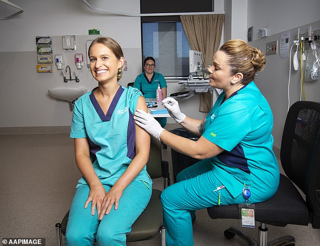 Registered nurse Zoe Park (left) receives the first Pfizer coronavirus vaccination in Queensland by clinical nurse consultant Kellie Kenway on February 22, 2021