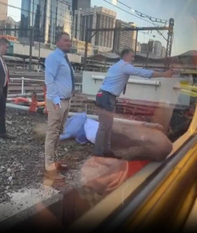 A man stumbles while trying to cross the tracks after a serious train delay in Melbourne on Saturday