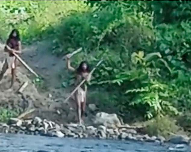 A Hongana Manyawa man holds up a stick to the bulldozer workers