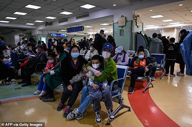 Children and their parents wait in an outpatient clinic at a children's hospital in Beijing as the city's hospitals are overwhelmed with cases of a new virus.  There are fears that the disease has also reached the US