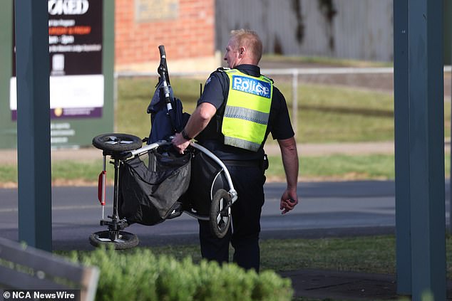 A police officer removes a pram from the tragic crime scene in Daylesford