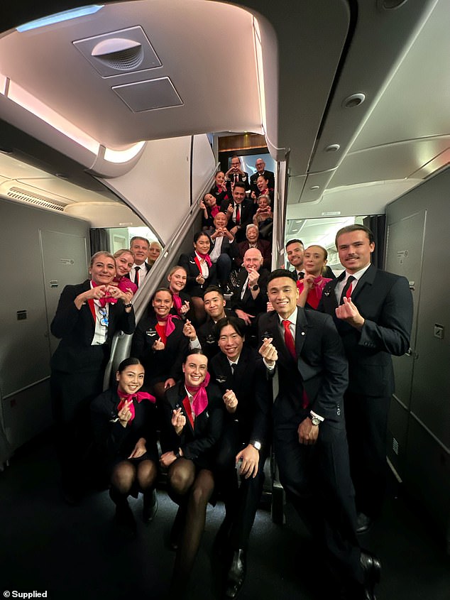 A beaming Ms Kam is pictured posing with her boyfriend John and more than 20 Qantas flight attendants on the special flight from Sydney to Hong Kong earlier this month