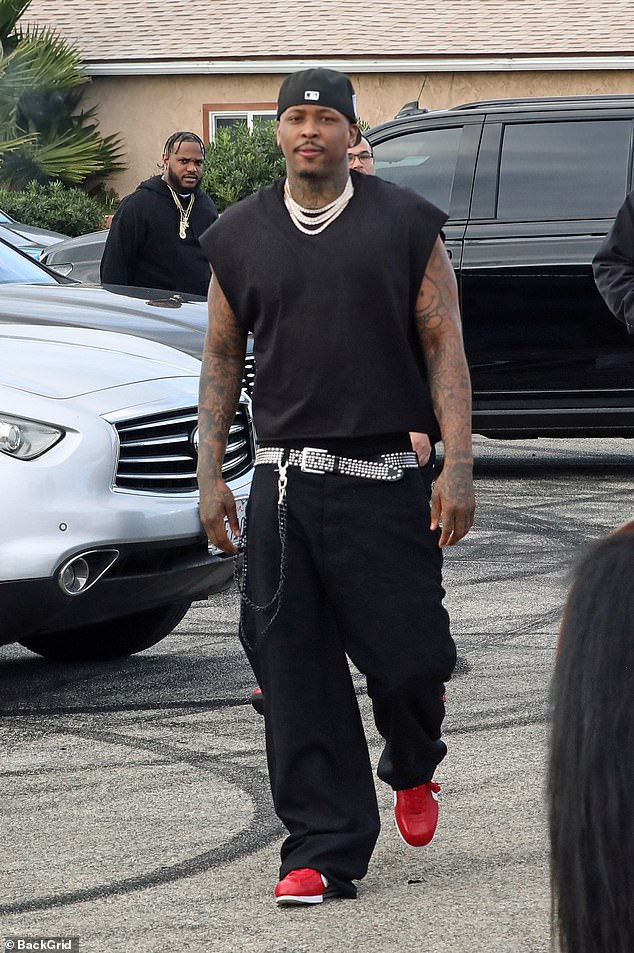 Volunteering: Rapper YG, 33, was flanked by security guards holding what appeared to be assault rifles as he volunteered at a Thanksgiving food drive in his hometown of Compton on Saturday