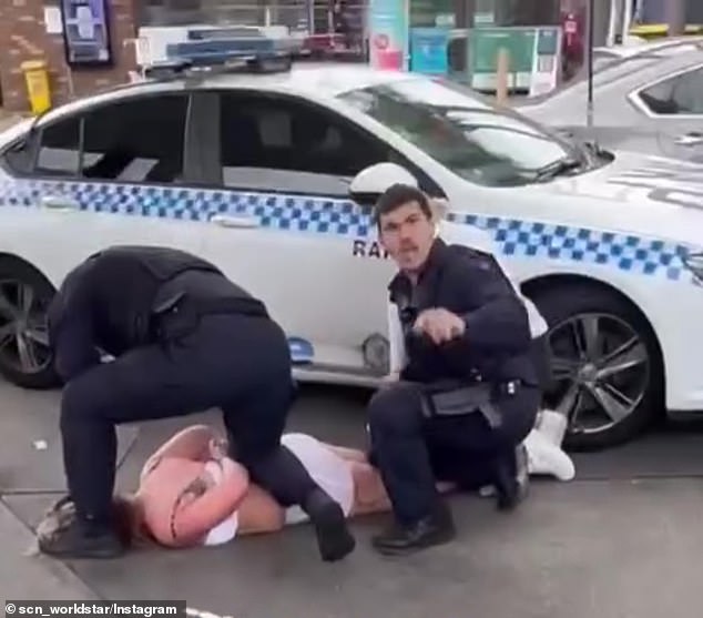 Video shows a young woman being pinned to the ground with her hands behind her back by several police officers at a busy petrol station on Railway Street, Rockdale, in Sydney's south-west, about 2.50pm on Tuesday