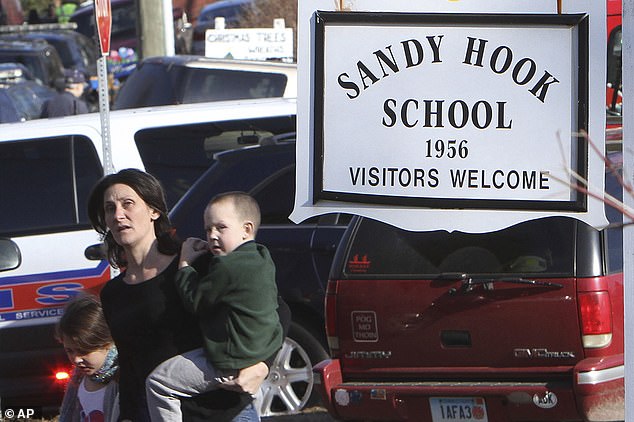 A parent walks away from Sandy Hook Elementary School with her children after a shooting at the school in Newtown, Conn., December 14, 2012