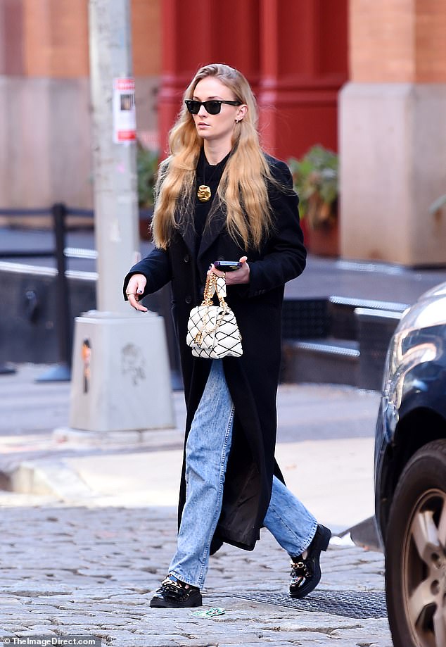 So chic: The blonde beauty – who is in the process of divorcing her husband Joe Jonas – looked Parisian chic in a long black winter coat that was unbuttoned.  The actress added distressed blue jeans and chunky black loafers with a gold chain over them