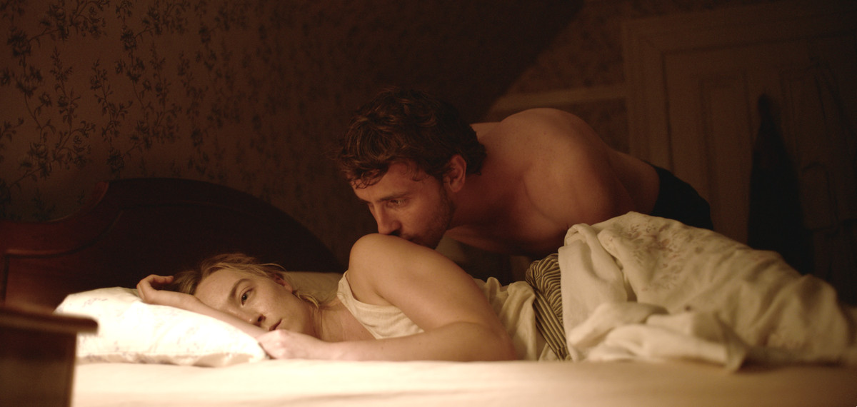 Hen (Saoirse Ronan) lies in bed looking despondent as Junior (Paul Mescal) gently kisses her shoulder