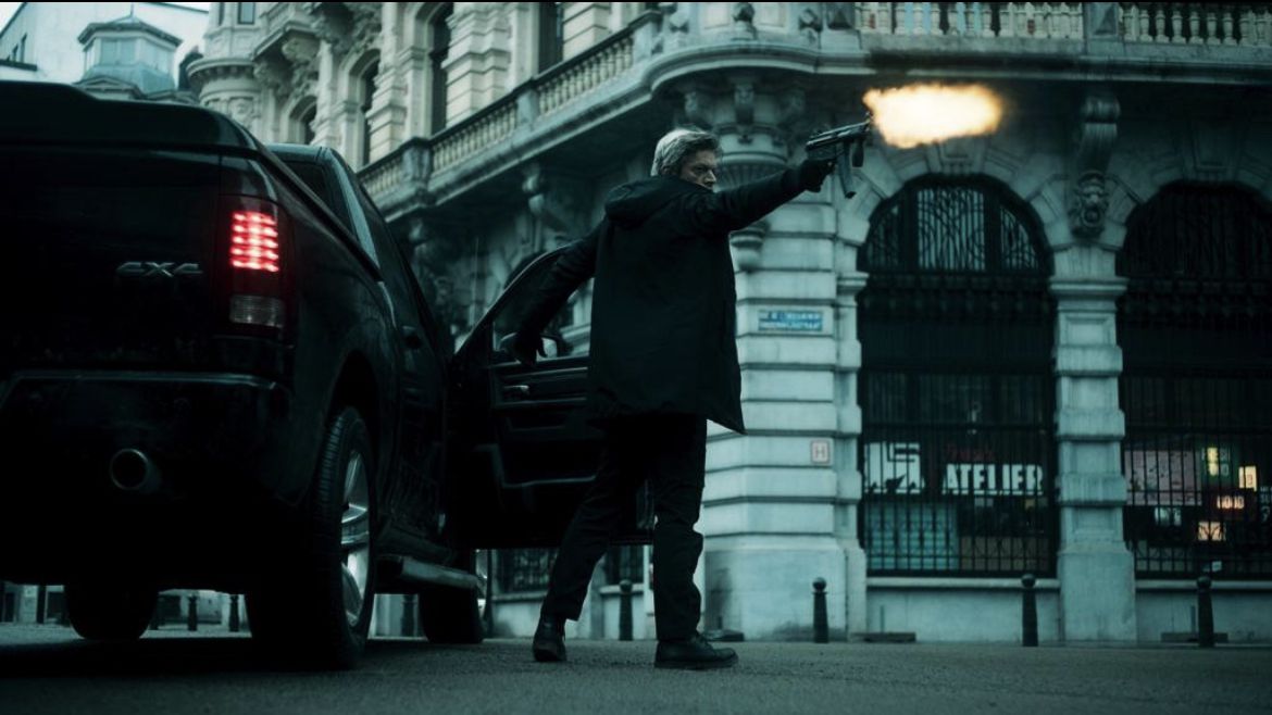 Samuel Jouy fires a submachine gun next to an open truck door in Ganglands.