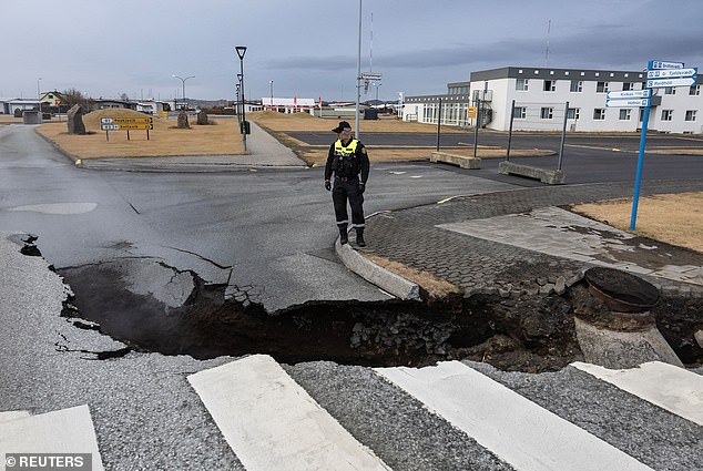 An Icelandic port is in serious danger of being destroyed by a threatened volcanic eruption, experts have told local media.  Pictured: A police officer inspects a crack in the road in the fishing village of Grindavik, November 15