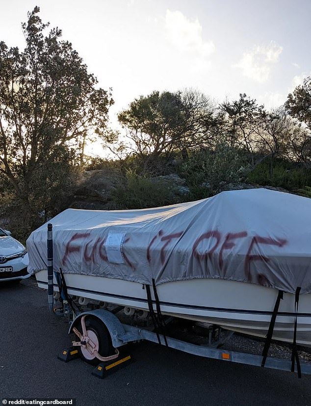 The owners of a boat parked in a street next to a popular beach have hit back after disgruntled locals spray-painted 'f*** it off' on the cover (pictured)