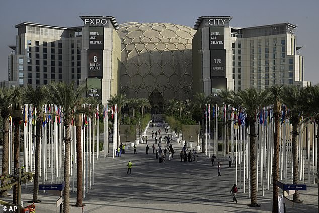 People walk through the venue for the COP28 UN Climate Summit with the Al Wasl Dome in the background in Expo City