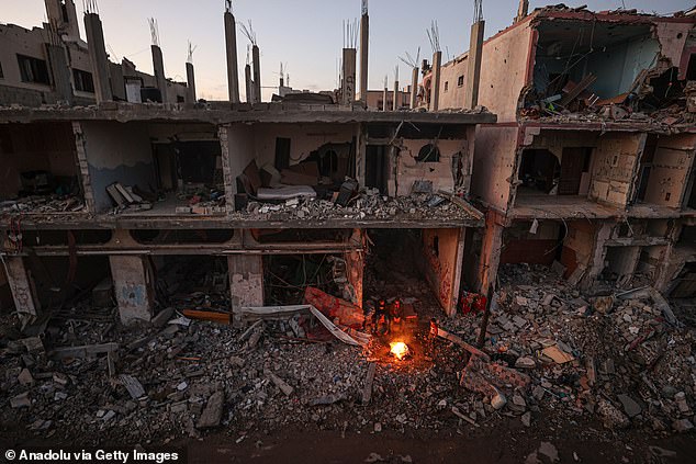 Gazans light a fire to keep warm in the remains of a house in Khan Yunis on Thursday