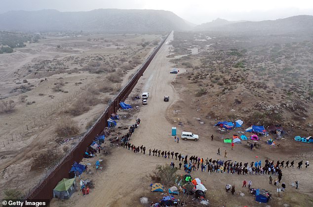 An aerial view of asylum-seeking migrants lining up to be transported to a U.S. Border Patrol processing center on November 30, 2023 in Jacumba Hot Springs, California