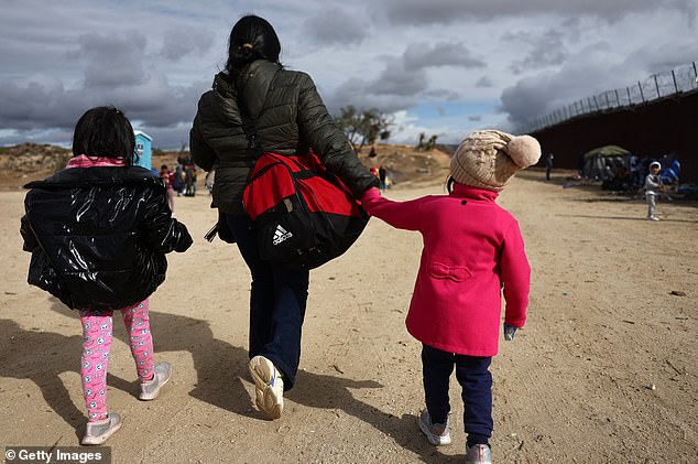 An Ecuadorian mother walks with her two daughters, ages four and six, toward a makeshift camp where they will wait to be processed by U.S. Border Patrol agents in California on Thursday.